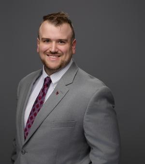 Portrait of TJ Carpenter in Grey Suit and Scarlet Tie